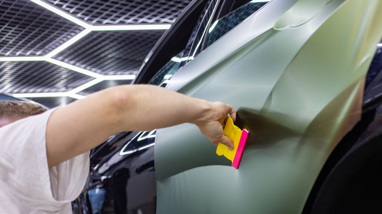 A specialist wraps a car with chameleon-colored vinyl film.