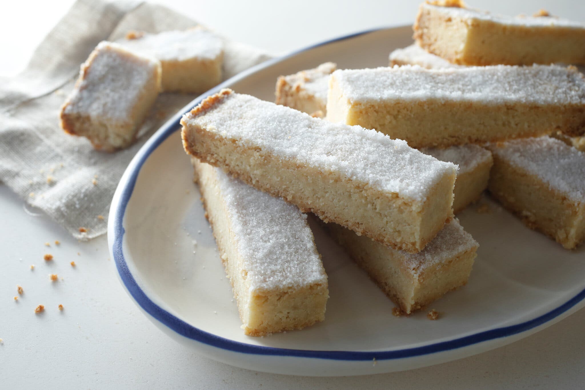 A plate of shortbread cookies dusted with powdered sugar, with a few crumbs scattered nearby.
