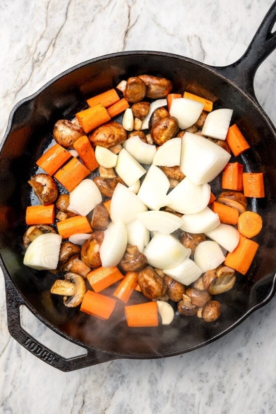 This Slow Cooker Coq au Vin is easier and lighter than the traditional version, but just as delicious with smoky bacon, mushrooms and onions. Vegetables in skillet for coq au vin.