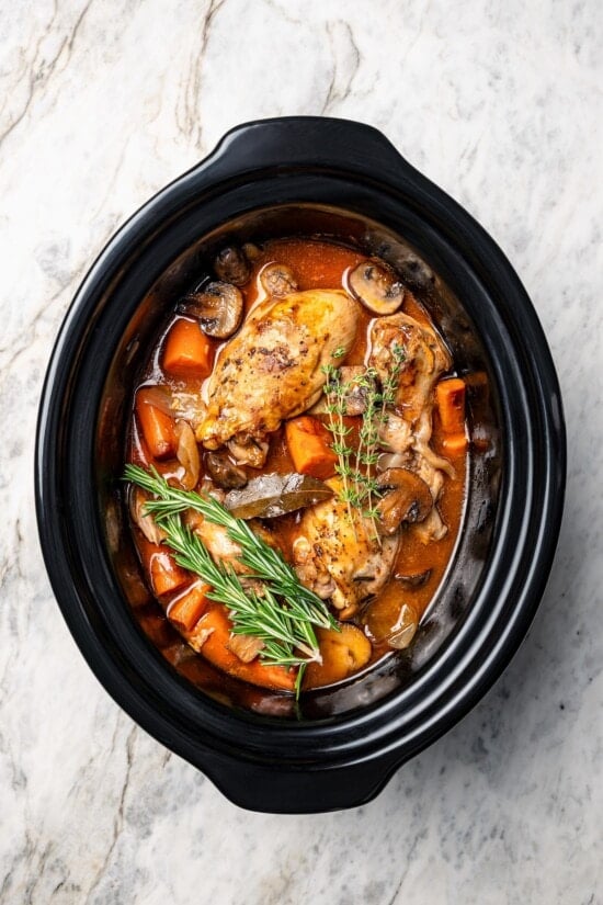 This Slow Cooker Coq au Vin is easier and lighter than the traditional version, but just as delicious with smoky bacon, mushrooms and onions. Slow cooker coq au vin in crockpot.