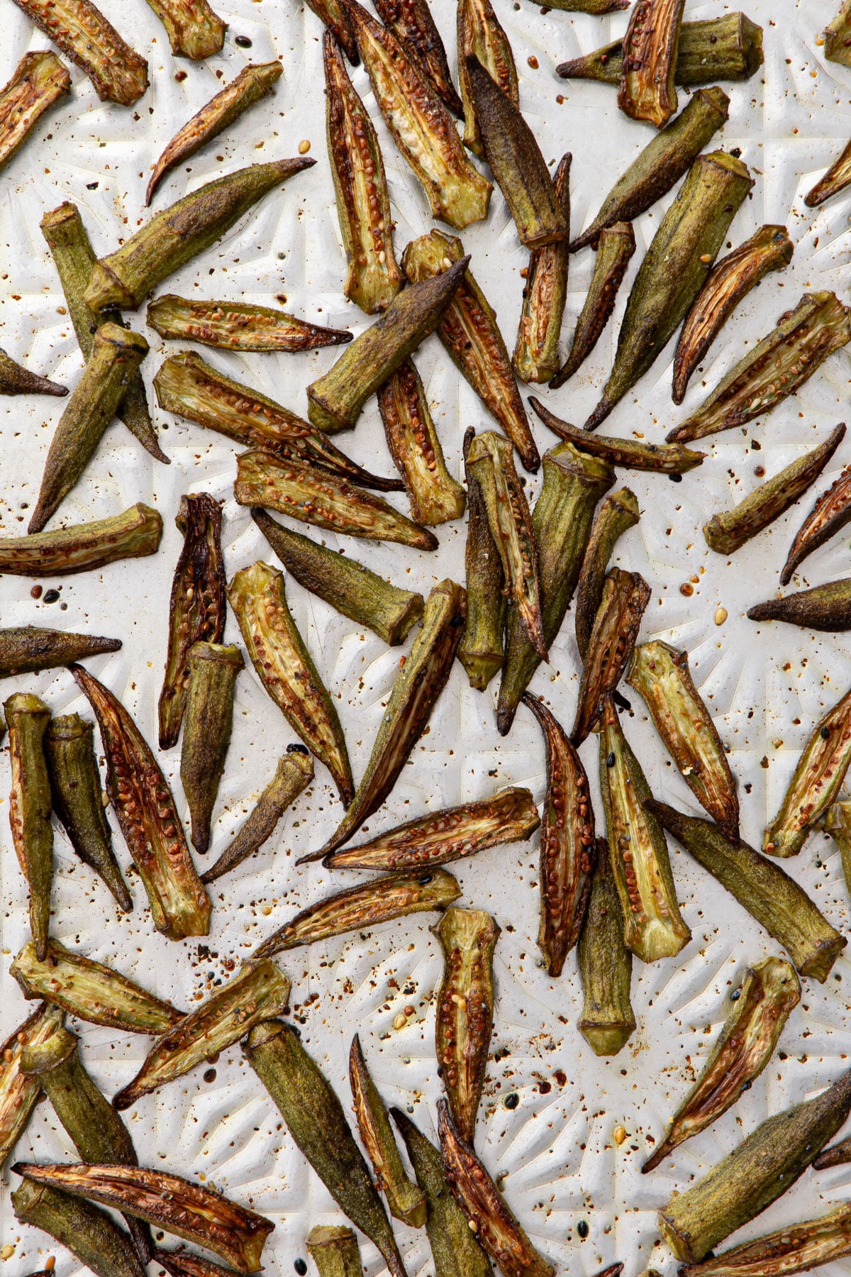 Overhead view of an aluminum cookie sheet with golden brown, crispy okra just out of the oven.