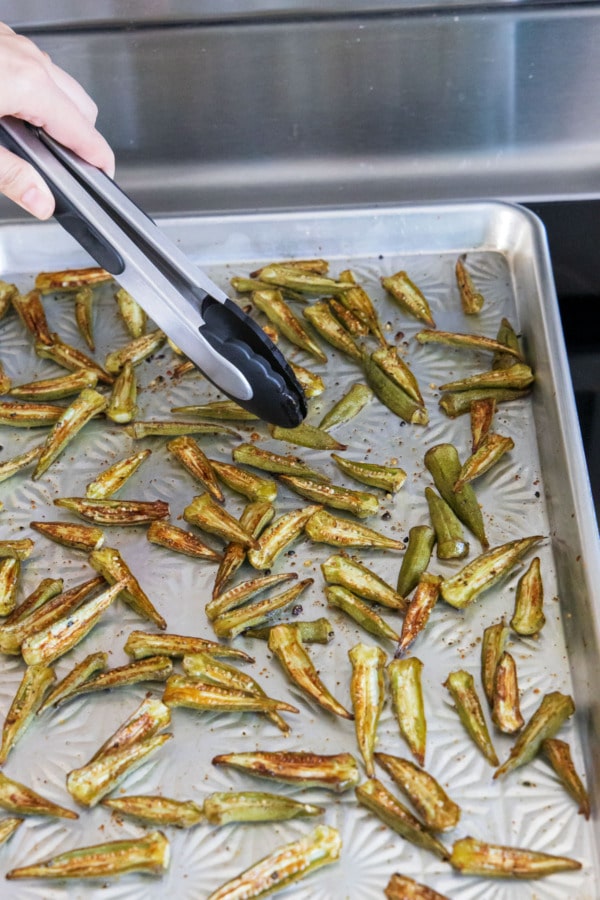 After partially baking, use tongs to flip the okra cut side up to finish baking.