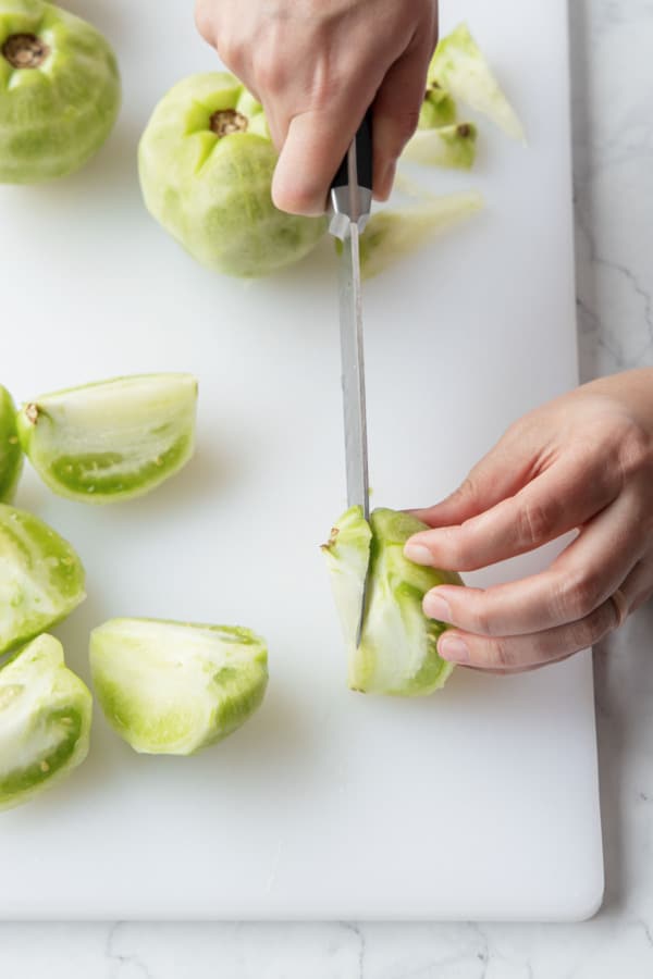 Cutting a wedge-shaped core out of the centers of the green tomatoes.