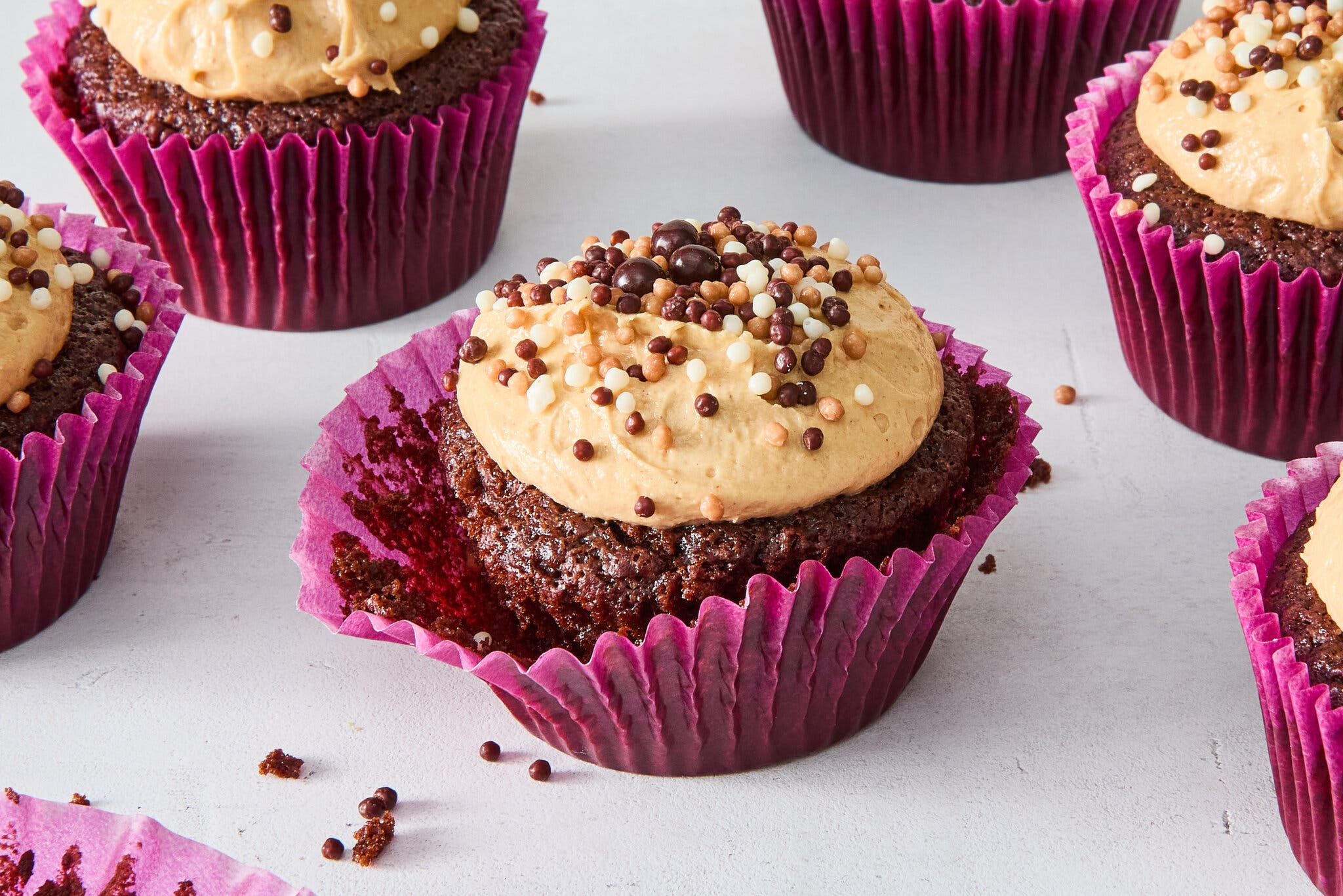 A side image of chocolate cupcakes topped with a light peanut butter frosting and sprinkles.