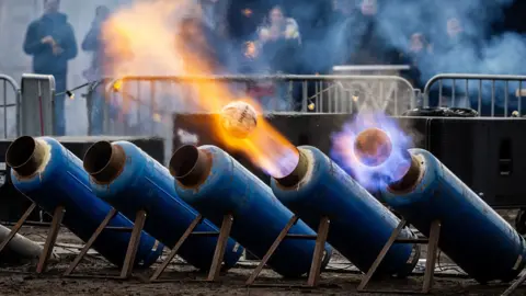 Shutterstock In Ommen, the Netherlands, milk cans fire footballs out the end of with lots of fire.