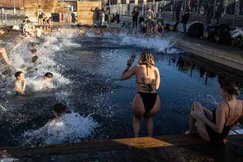 Getty Images A group of people jumping in a cold water pool making a splash
