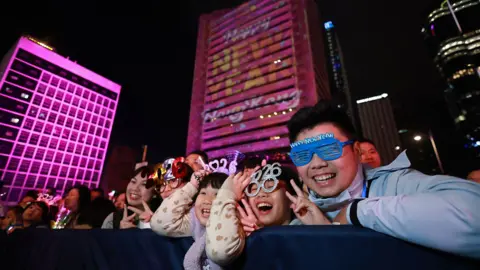 AFP via Getty Images People watch live performances and a light show during New Year's Day celebrations in Hong Kong on January 1, 2026. 