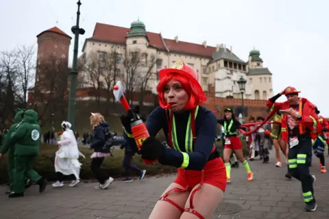 Getty Images People dressed up in different costumes, including firemen and women, run in the New Year's Eve Run in Krakow, Poland