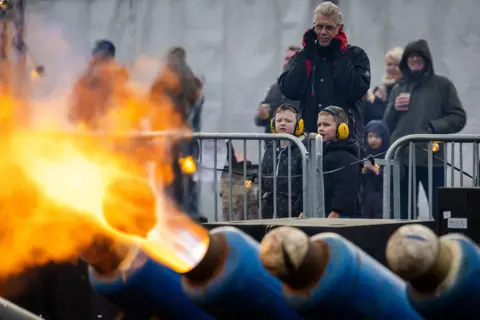 Shutterstock In Ommen, the Netherlands, milk cans fire footballs out the end of with lots of fire as families look on