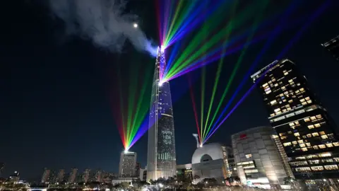AFP via Getty Images Laser lights illuminate the midnight sky over the Lotte World Tower, South Korea's tallest building in Seoul