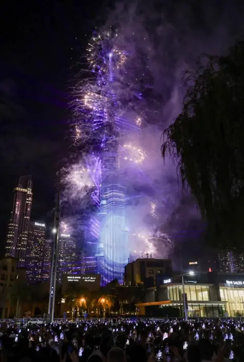 Reuters People hold their phones and watch fireworks near the Burj Khalifa during New Year's celebrations in Dubai