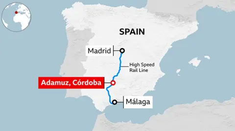 A map of Spain highlighting a section of the country’s high‑speed rail network. A blue line marks the high‑speed rail route running between Madrid in central Spain and Málaga in the south. A red dot marks Adamuz in the province of Córdoba near the midpoint of the route, where the two trains collided. 
