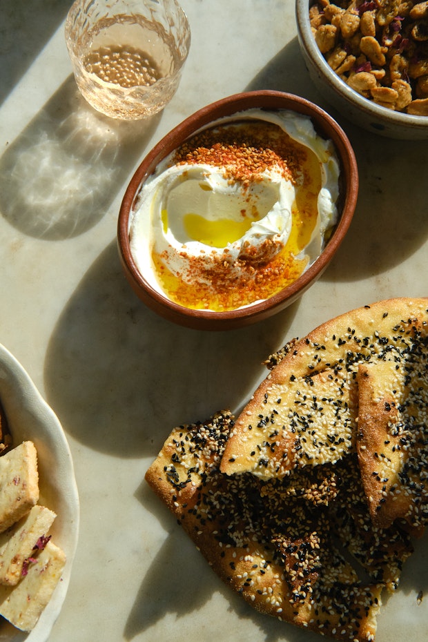 Smoked labneh, seeded flatbread, candied peanuts on a marble table