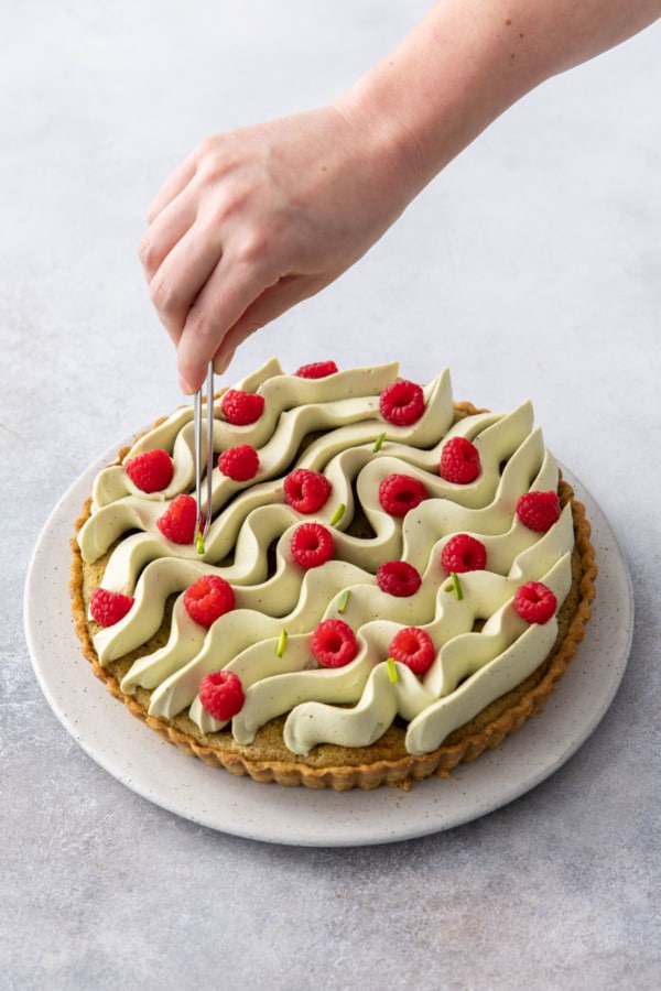 Placing slivered pistachios on top of the tart with tweezers.