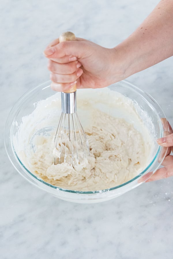 Stirring sourdough waffle batter until just incorporated.